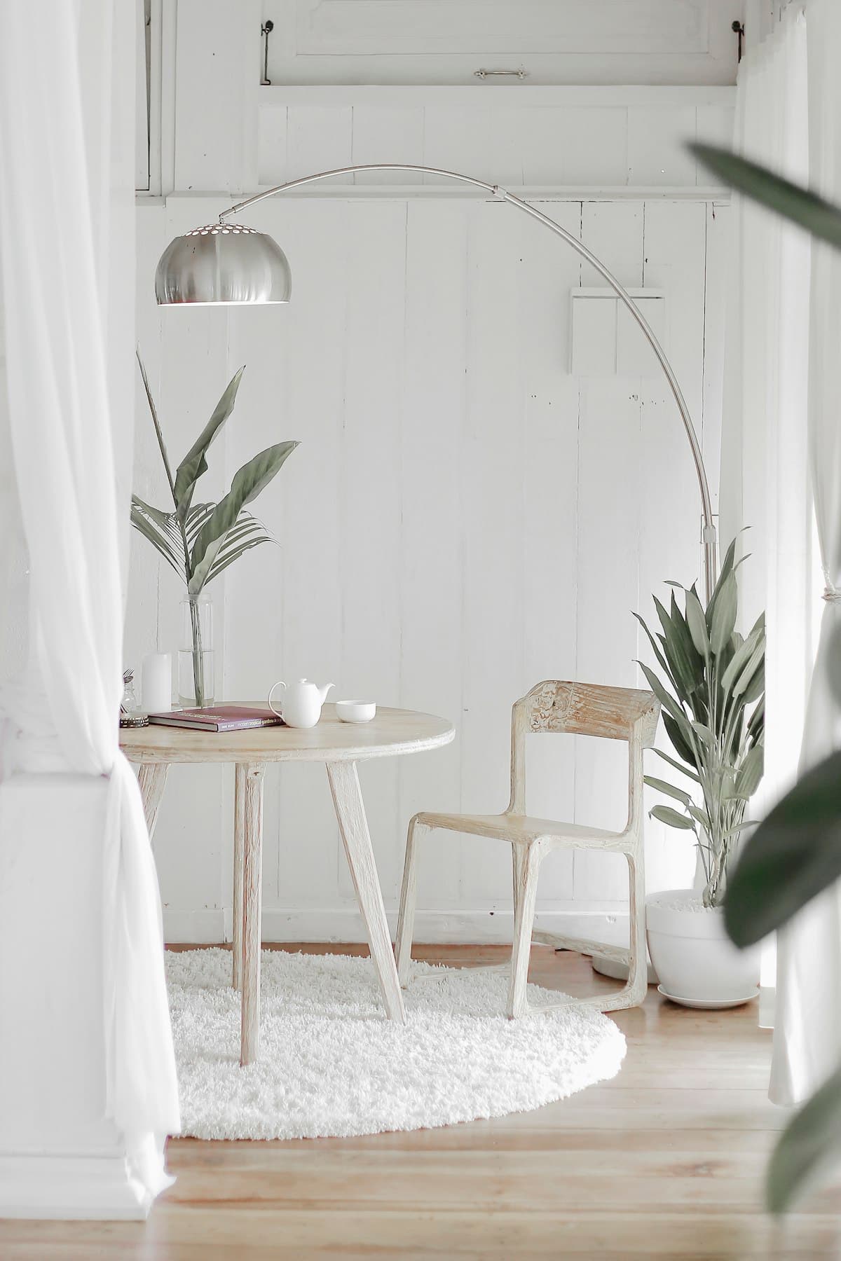 A calm white room with morning light, linen curtains, and green plants